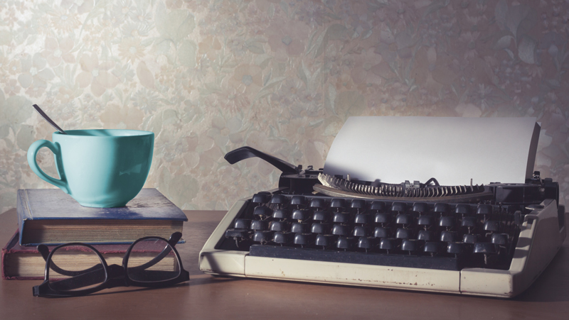 Photo of typewriter with book and cup