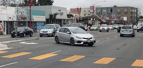 A highly visible crosswalk with cars in the background