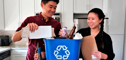 couple placing items in recycle bin