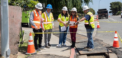 City staff inspecting the construction of a sidewalk at a corner on Encinitas Avenue 