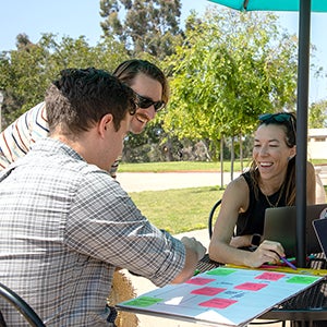 Performance and Analytics staff collaborating on a workflow at a table outdoors