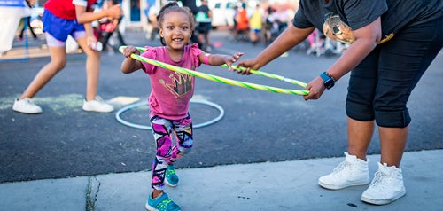 A smiling child using a hula hoop