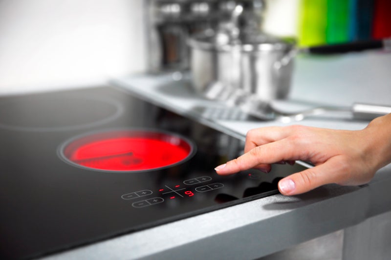 A person kneeling in front of a washer and dryer doing laundry