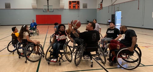 People in wheelchairs playing basketball at an indoor gym