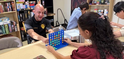 A San Diego police officer playing Connect Four board game with a teenager