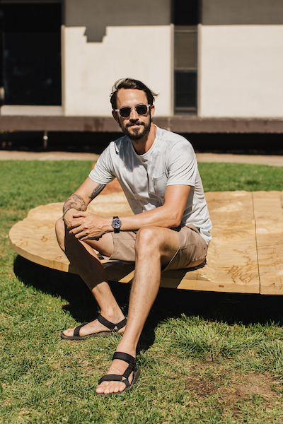 Trevor Amery sitting on a wooden circular platform on top of grass