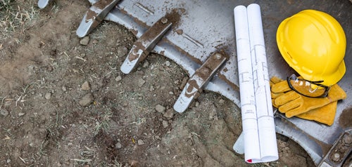 Plans and safety equipment on top of a heavy equipment bucket.