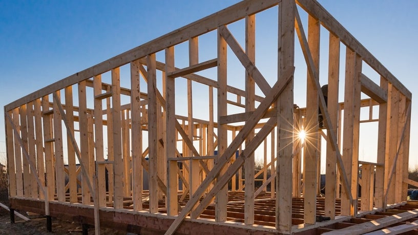 The wooden frame of an Accessory Dwelling Unit in construction with the sun in the background. 