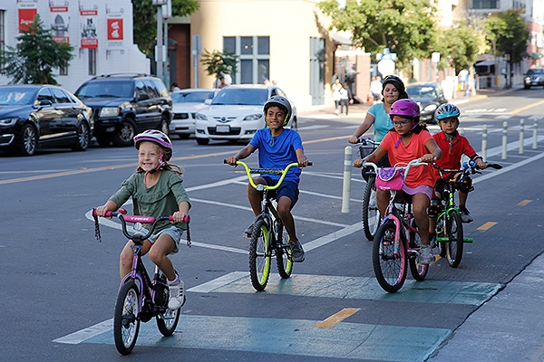 Children riding bikes on a bike lane in a downtown street
