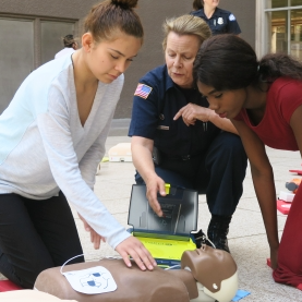 Three person demonstrating how to perform CPR