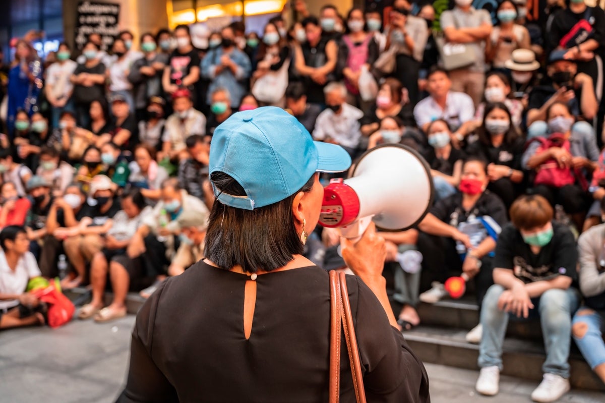 Woman speaking on megaphone in front of crowd