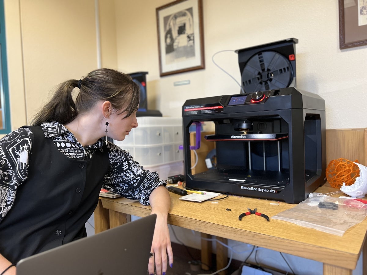 Staff with laptop and a 3D printer printing