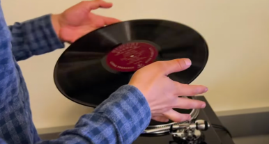 Closeup of a person's hands holding up a vinyl record to be digitized at the Digital Memory Lab, located in the 4th floor IDEA Lab