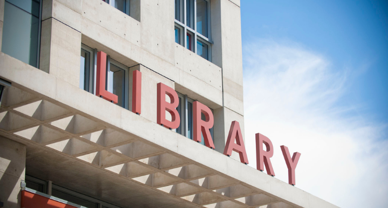 Exterior close up of San Diego Central Library showing red letters spelling out "Library" on top of an architectural ledge