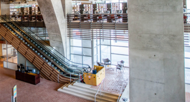Interior of lobby, featuring paneled escalators and concrete “stonework” 