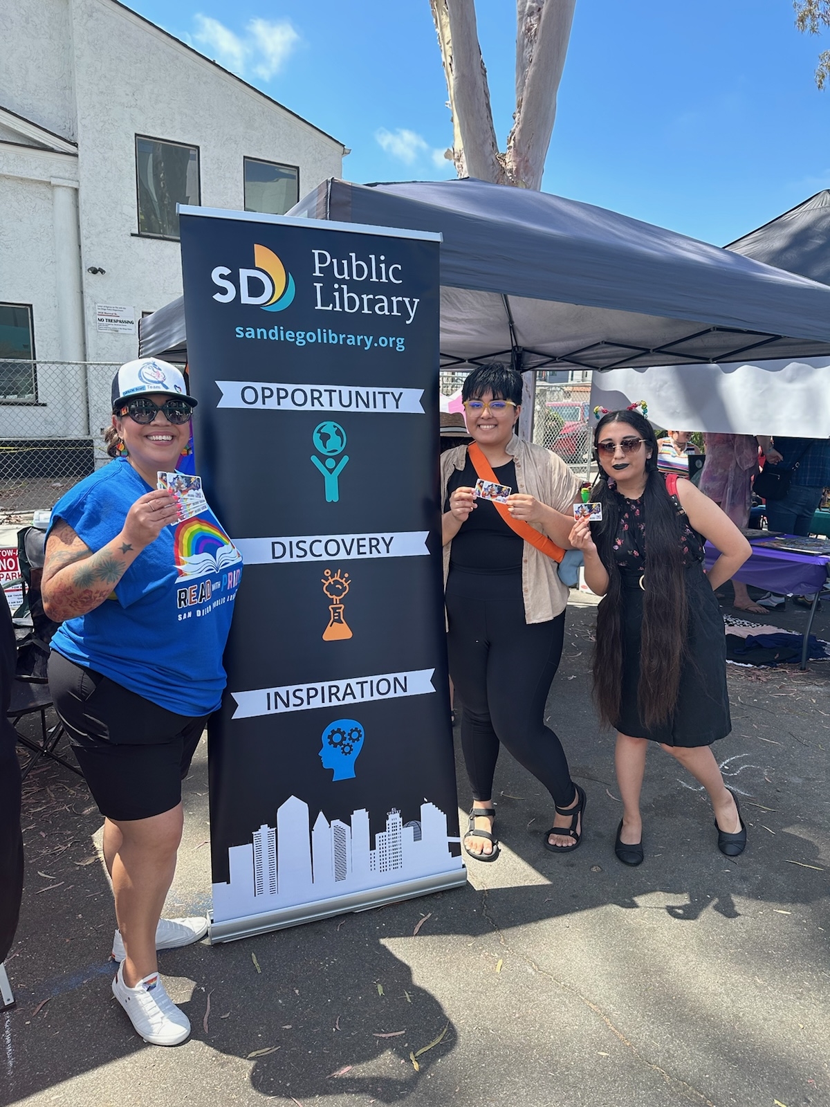 Three people standing next to San Diego Public Library banner