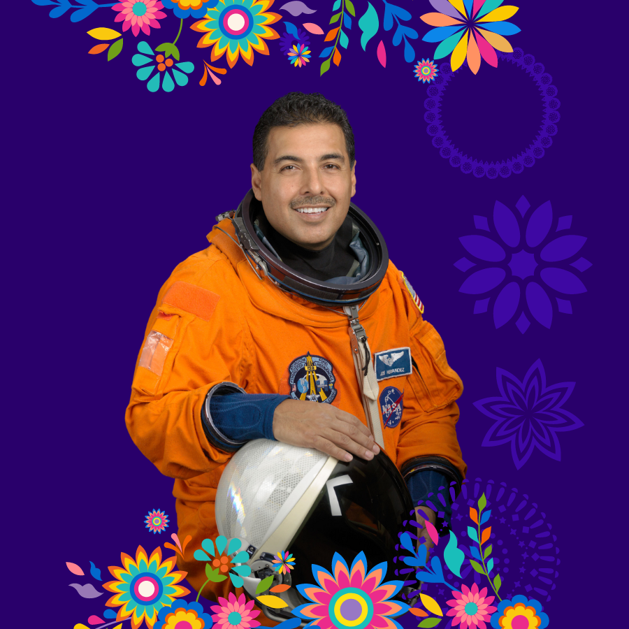 The Mexican-American astronaut, Jose M. Hernàndez, smiles proudly at the viewer with his helmet under his hand.