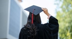 a person in a graduation gown is holding their cap