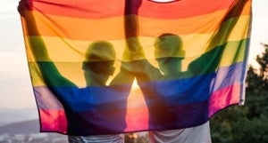 two people holding up a rainbow flag