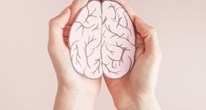 two hands holding a paper cutout of a brain