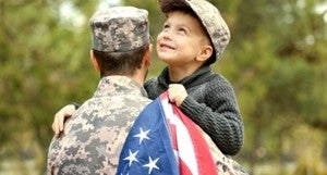 a child is holding an American flag in the arms of a soldier