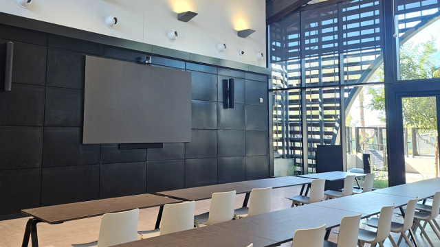 The community room  featuring a large video display and floor-to-ceiling windows. 