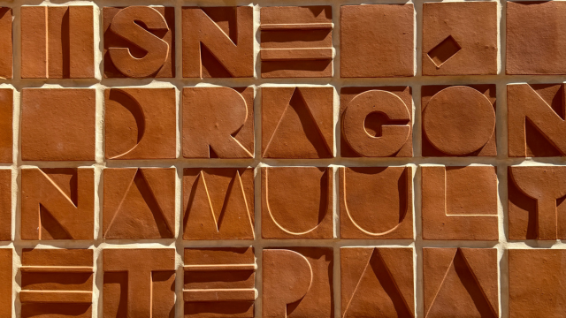 Closeup of artist Janelle Iglesias’s “Text/Tile” terra-cotta wall tiles in the building courtyard. 