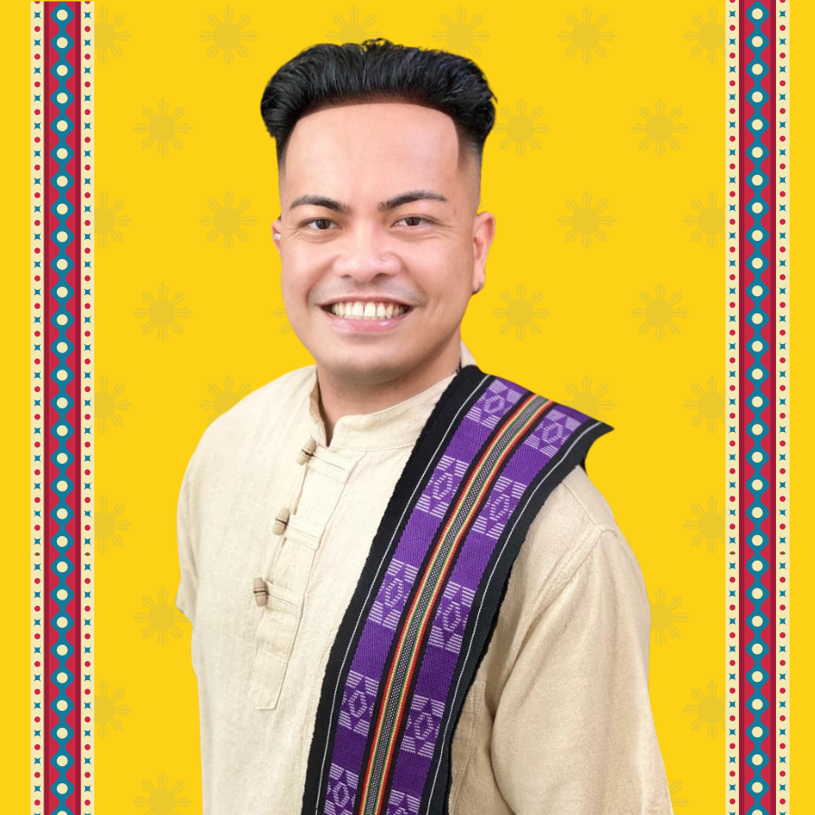 Professor JA Ruanto-Ramirez is photographed smiling, they wear a barong tagalog, set in a background of yellow.