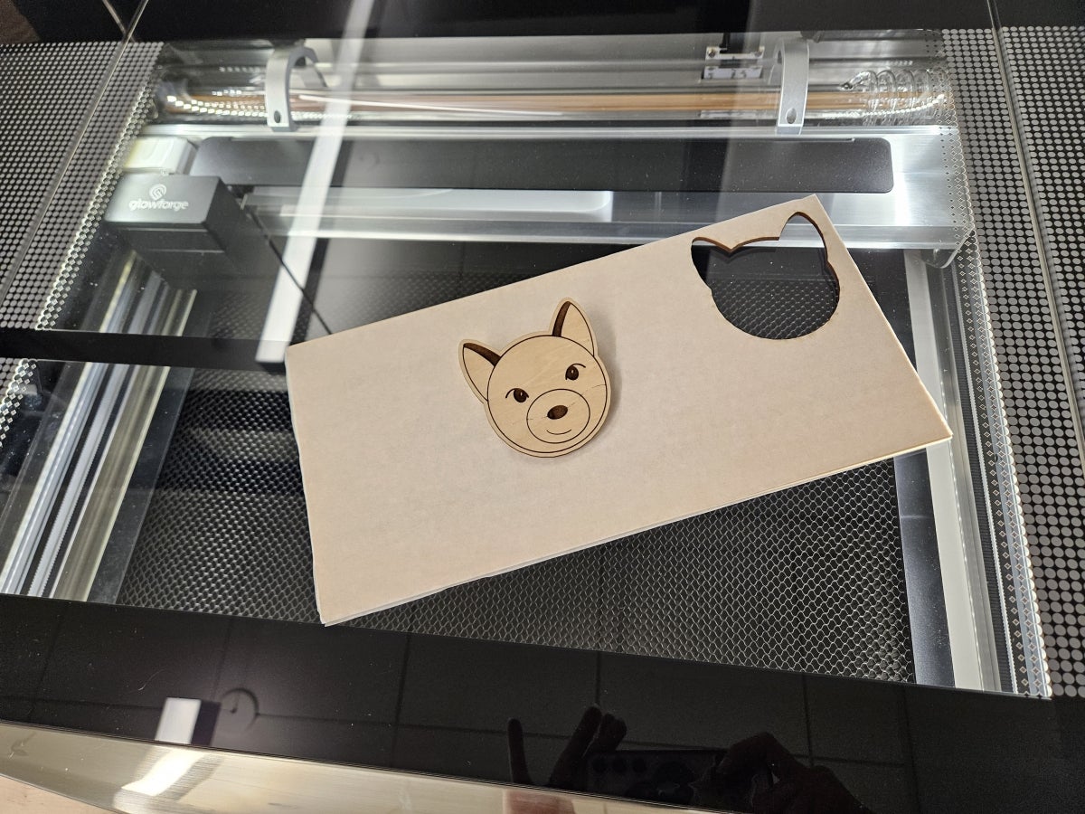 Photo of a Glowforge laser cutter with an engraved ODI on wood.