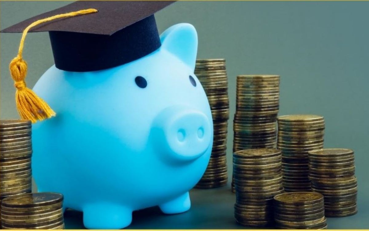 Blue piggy bank wearing graduation cap surrounded by stacks of coins