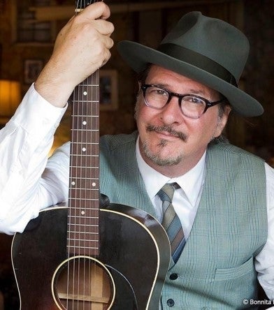 Headshot of Gregory Page holding a guitar vertically.