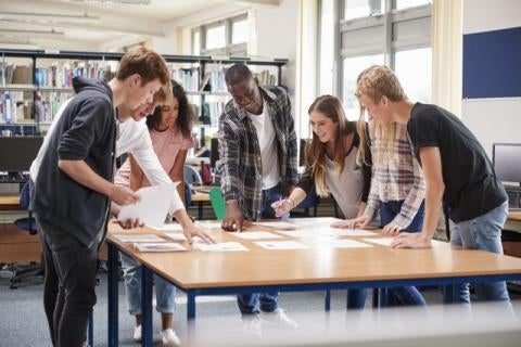 Young adults gathered around a table looking at papers