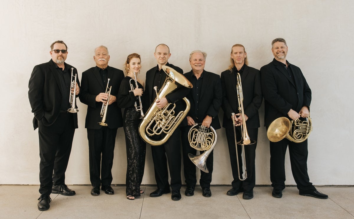 seven musicians in black holding their brass instruments.