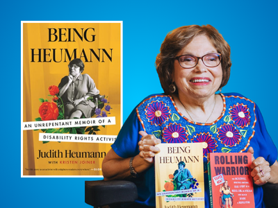 Author Judith Heumann holding her books; book cover of "Being Heumann" in background