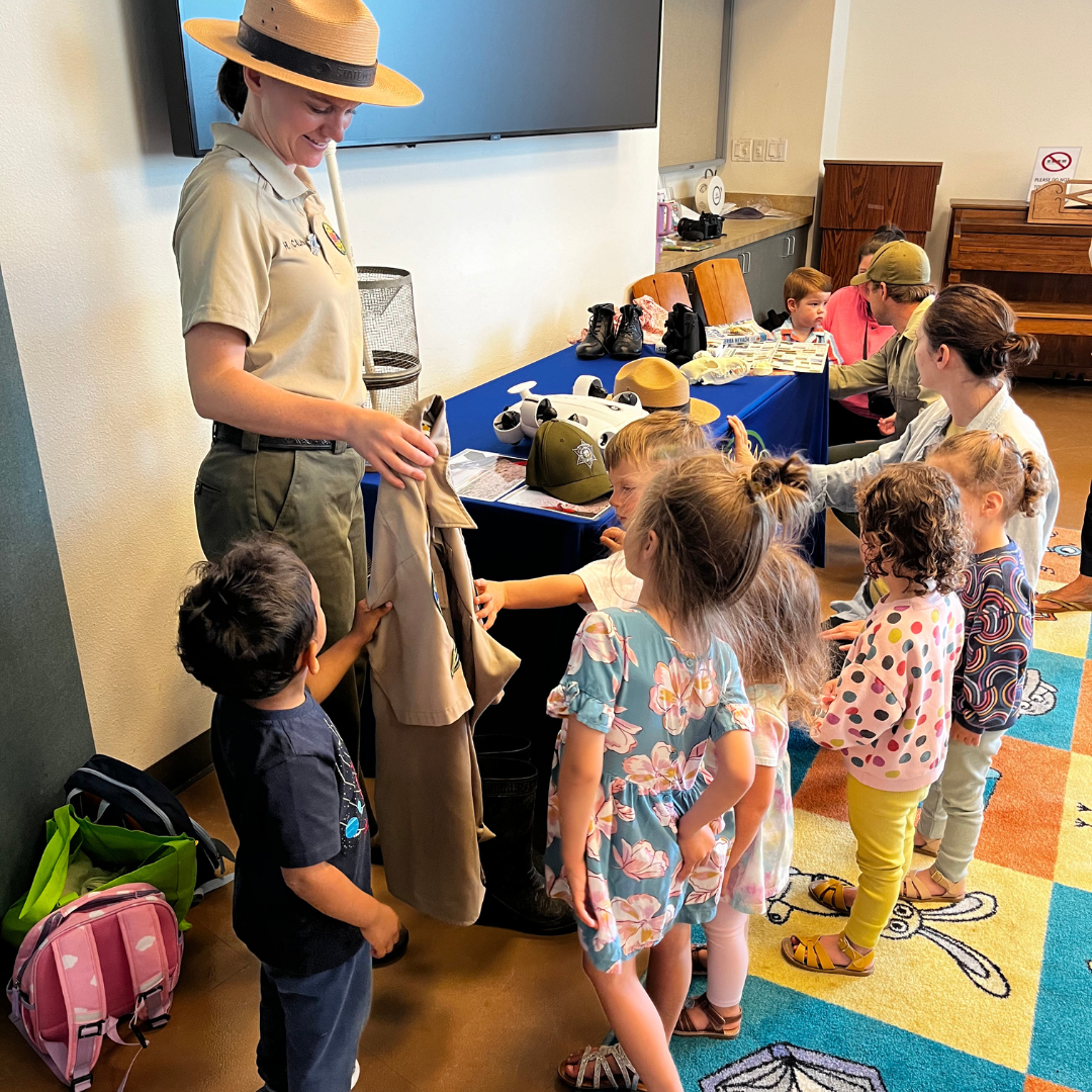 A group of young children are enjoying park ranger storytime during the summer lunch program.