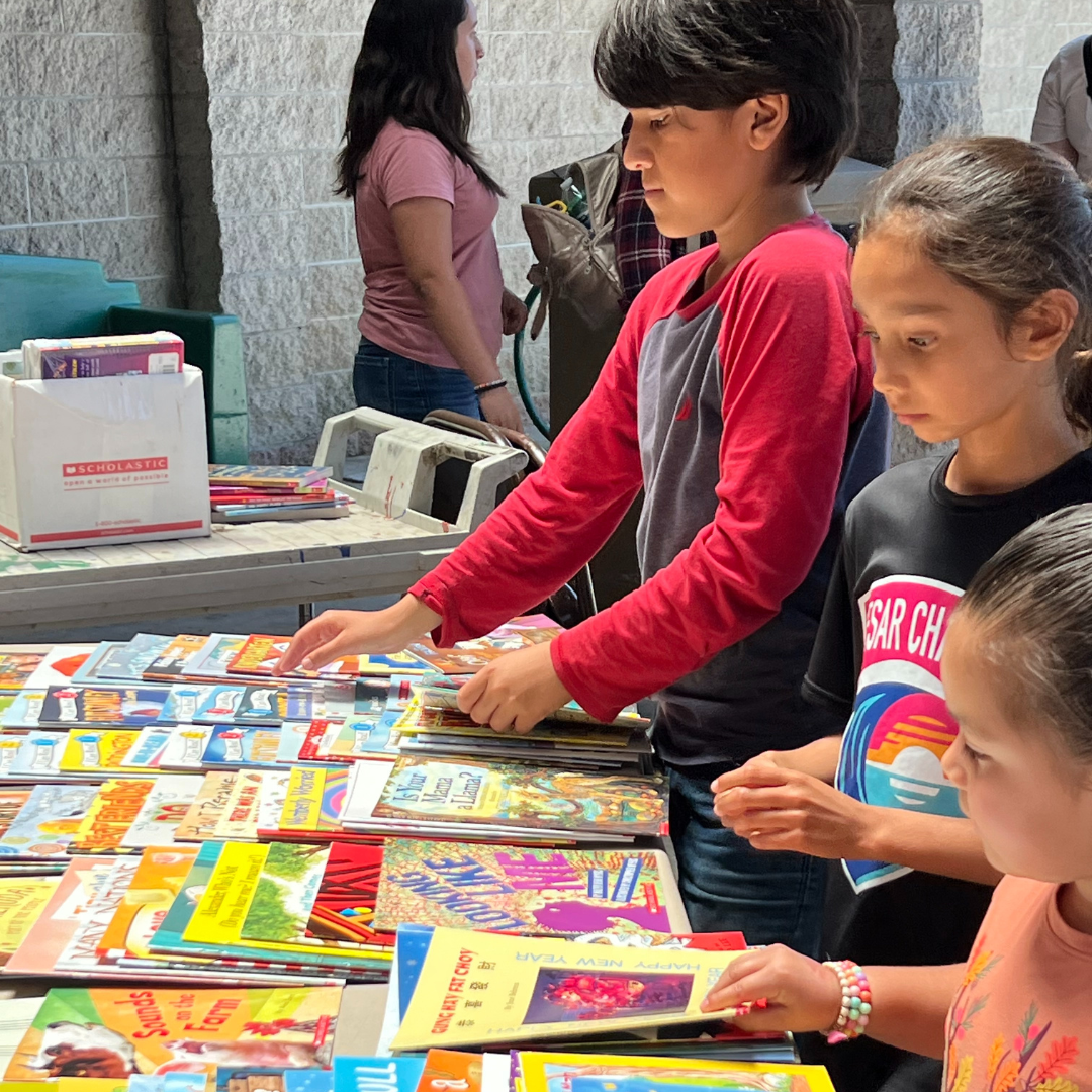 3 children are selecting books that they can take home to build their home library during the summer lunch program.