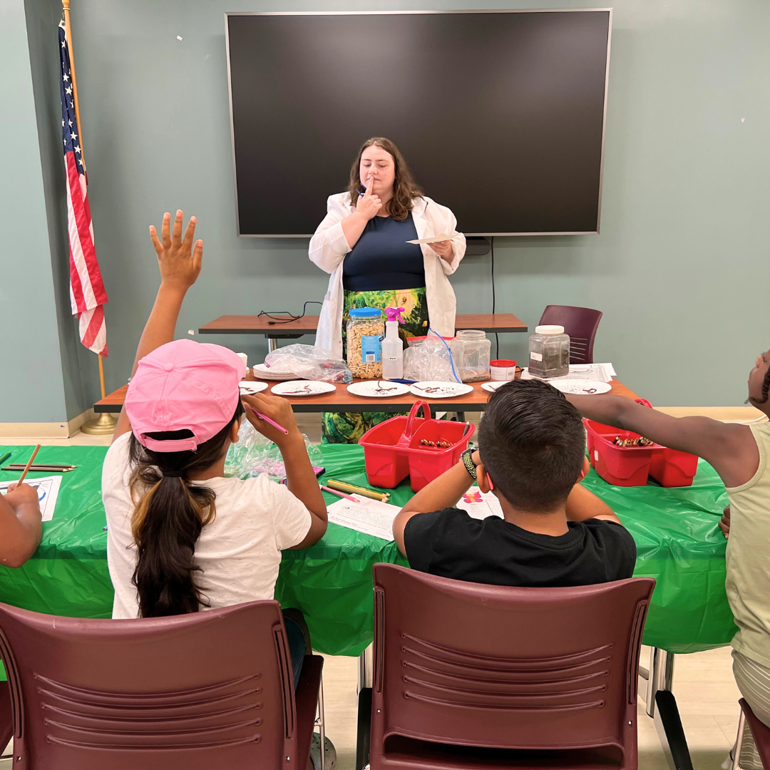 a group of students are attending a science workshop with a teacher in a white lab coat.