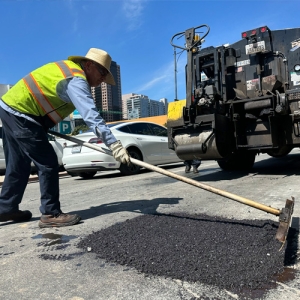 City worker covering a pothole with asphalt