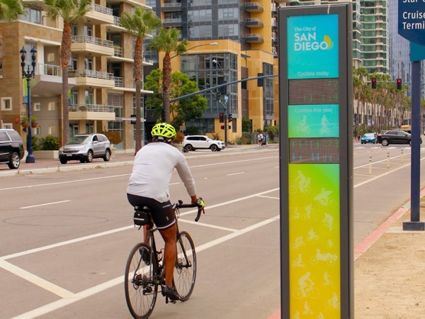 Bike rider riding by Bike SD sign