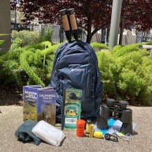 Backpack next to parks pass, binoculars, flashlight, emergency gear and more