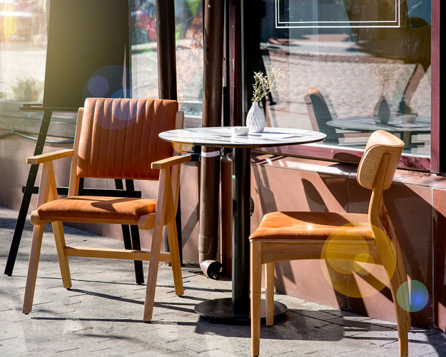 A dining table and chairs on the sidewalk outside a restaurant